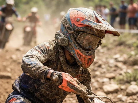 Riders on a dusty dirt trail, with the lead rider prominently displaying an off-road headset on their helmet